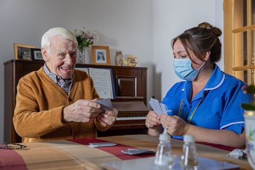 A Bluebird Care assistant playing cards with a happy customer
