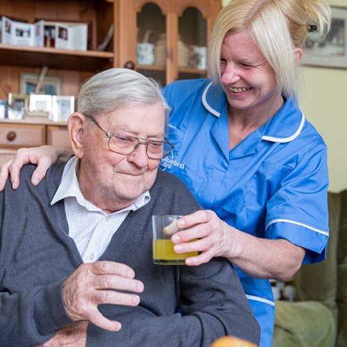 Bluebird Care live-in care assistant giving a happy customer a drink