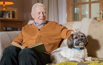 man and dog sitting on a sofa home care